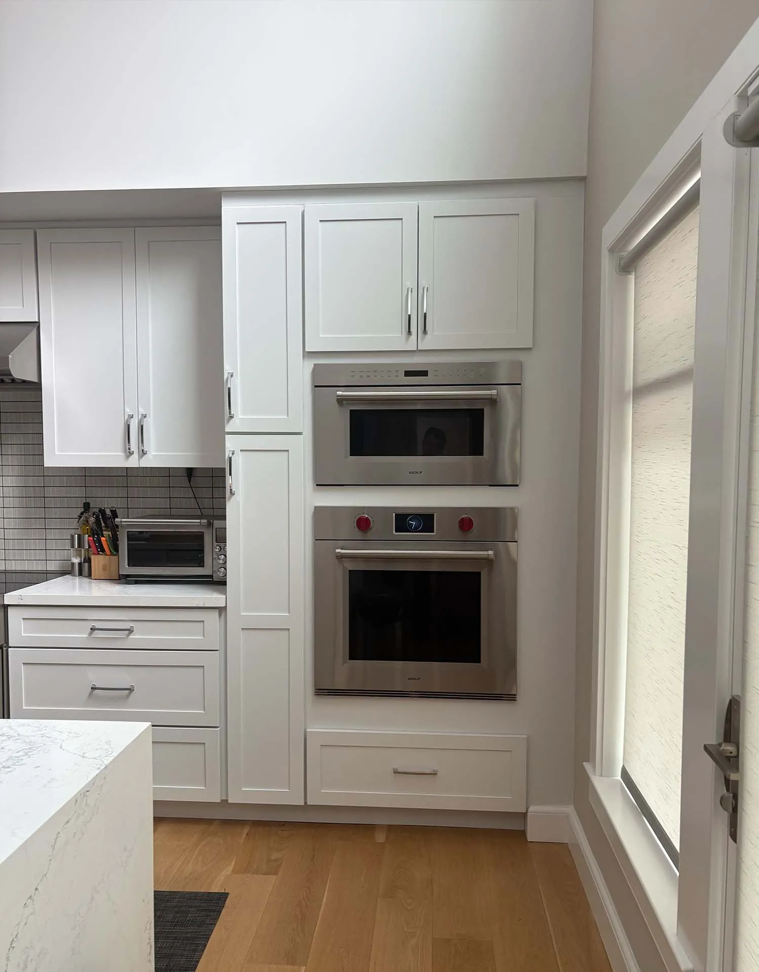 White shaker kitchen with a professional range and wall ovens